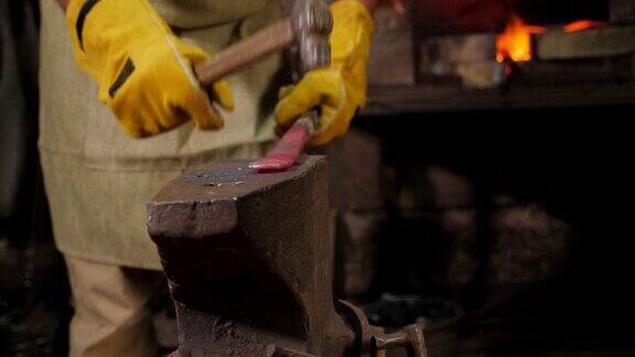 两个铁匠正在铁匠铺里用铁锤敲打铁砧上的热金属