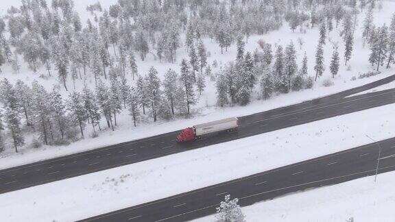 无人机:大型商用卡车在危险的结冰公路上拖着一个沉重的集装箱