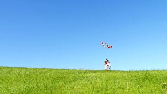 孩子们带着风筝在绿色的山顶上奔跑