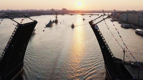 清晨在俄罗斯海军节日之前涅瓦河上的空中景象与军舰军舰从一座升起的吊桥下通过最新的巡洋舰在标志性的宫殿桥中
