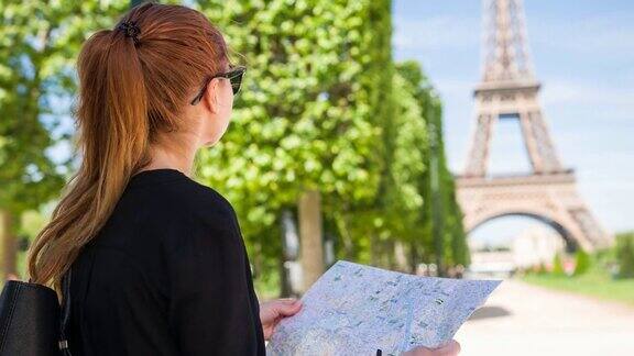 女游客在战神广场花园拿着巴黎城市地图看着埃菲尔铁塔