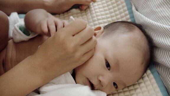 母亲用棉签给新生婴儿清洗耳朵