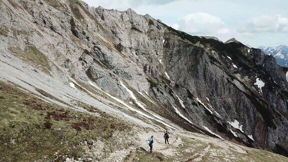 这是一对夫妇在奥地利阿尔卑斯山锡纳贝尔地区徒步旅行的全景无人机拍摄山坡上仍有部分被雪覆盖着多石和尖锐的山有点阴天探索自然