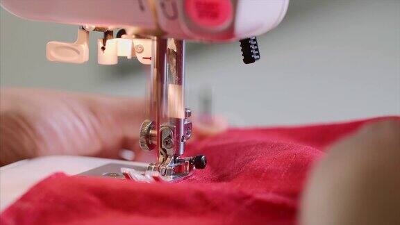 女裁缝的手在缝纫机上用直缝缝红衣服