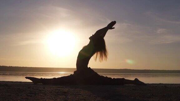 日出时海滩上瑜伽女孩的剪影