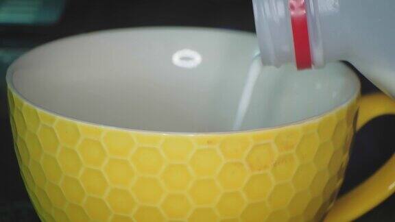 牛奶倒进一个黄色的六角形杯子里
