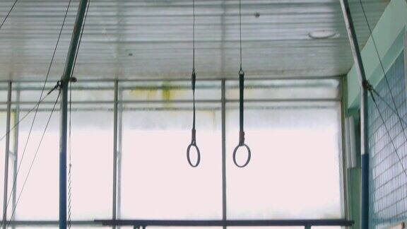 体操吊环悬挂在一个铁拱上在体育馆里训练