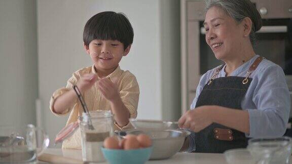 6岁的亚洲华人男孩在厨房柜台上用面粉烘焙帮助祖母准备食物