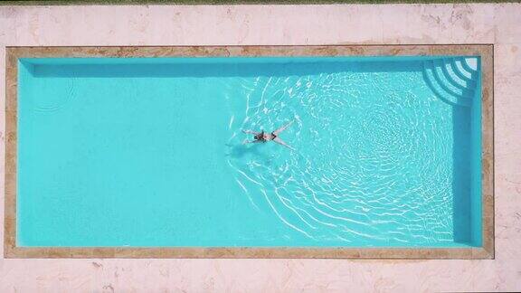 一名女子在私人别墅游泳池游泳的鸟瞰图