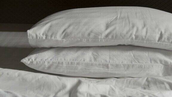 两个枕头乱成一团白色的毯子凌乱不堪早上醒来后发现床上有羽绒被