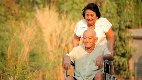 一位老妇人推着她残疾的丈夫坐轮椅