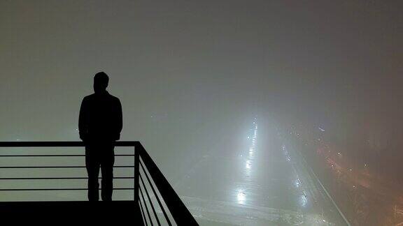 这个男人站在阳台上以雾蒙蒙的城市为背景hyperlapse