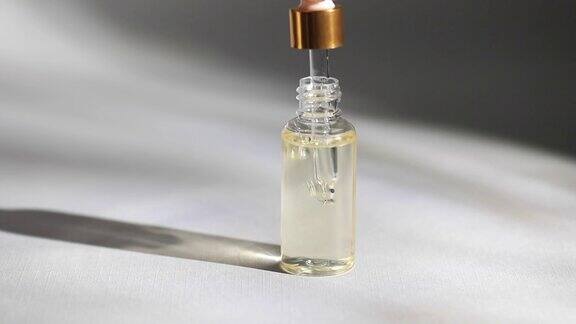 一个玻璃滴管瓶的模型一滴油从化妆品吸液管上滴下来