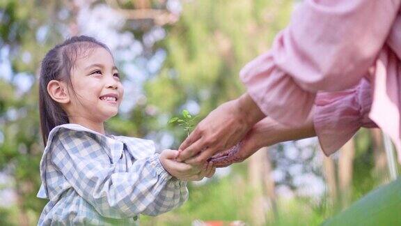 可爱的小亚洲女孩把小植物送给妈妈拯救地球的理念