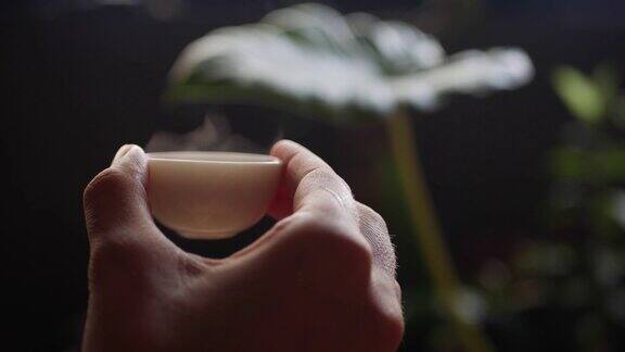 女人拿着一个装着中国乌龙茶的小茶杯传统的中国功夫或功夫茶道中国传统文化元素特写镜头4k