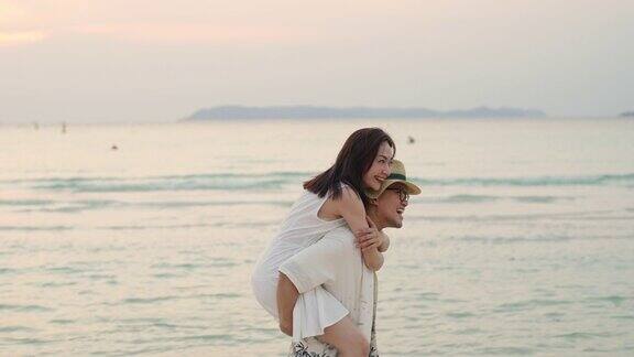 4K的亚洲情侣在夏日夕阳下一起走在海滩上