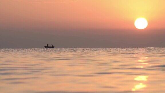 清晨在橙色的太阳下渔民们驾着小船出海捕鱼