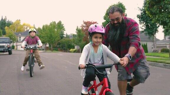 美国土著父亲帮助他的小女儿学习骑自行车
