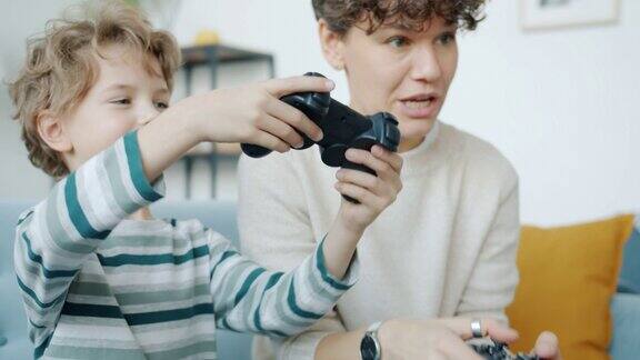 母亲和儿子在家里用操纵杆玩电子游戏笑着击掌