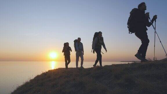 在海边的山顶上行走的四个旅行者慢动作