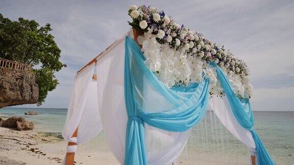 热带海滩上的婚礼拱门装饰着鲜花和大型迎风织物菲律宾保和