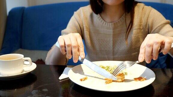 一个面无表情的女人在咖啡馆用刀叉吃蔬菜沙拉