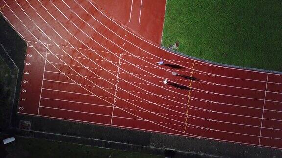 在体育场的男子跑道上亚洲的中国男运动员在雨中奔跑