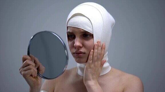 女性穿着松紧带头巾照镜子整容后感到疼痛