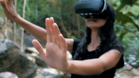 美丽年轻的黑发女人使用虚拟现实眼镜在丛林