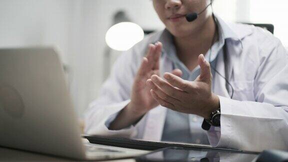 亚洲男子医疗有视频呼叫远程病人在笔记本电脑在办公室