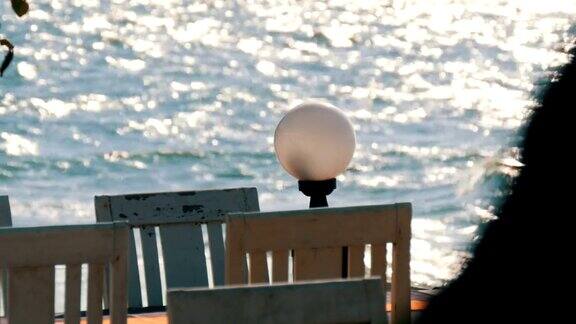 空荡荡的咖啡馆白色的木椅放在海边海浪向阳光倾泻而下海边的咖啡桌