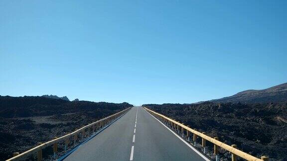 在一个空的道路上通过一个火山景观从黑色熔岩覆盖火山泰德特内里费加那利群岛