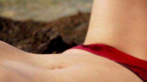 女性腹部日光浴在海滩上