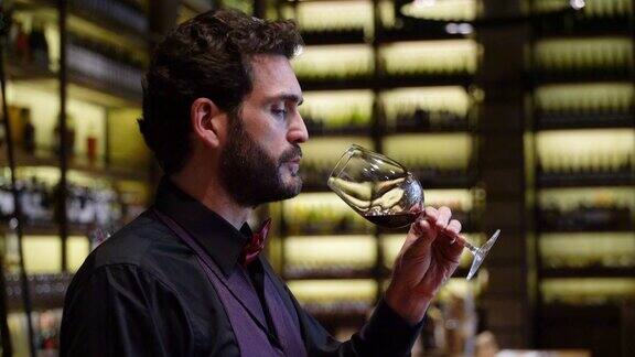 男侍酒师一边品尝葡萄酒一边在酒窖工作