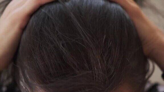 一位中年妇女抚摸着她乌黑的头发头发的根部有一头灰白的头发