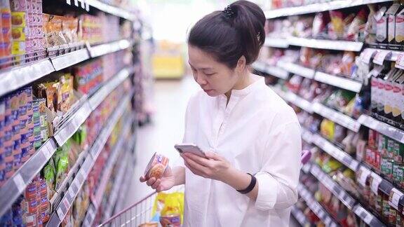 亚洲女性使用智能手机在超市购物