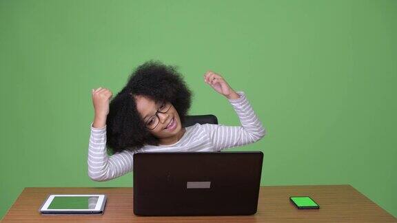 年轻可爱的非洲女孩与非洲发型使用笔记本电脑