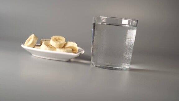 香蕉片放在一个白色的盘子里在一个灰色的背景用清水雾化