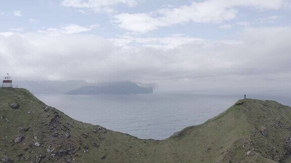 无人机飞越kallur灯塔位于卡尔索伊岛与绿色崎岖悬崖山面在丹麦法罗群岛