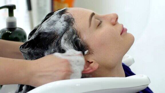 发型师服务年轻女性到美容院洗发