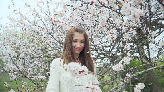 美丽的女孩在春天开花的树旁