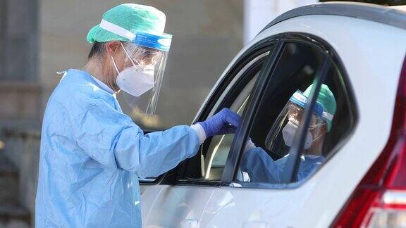医护人员佩戴EPI对车内的患者进行PCR检测以检测患者是否感染COVID-19