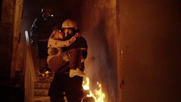 燃烧的大楼一组消防员从燃烧的楼梯上下来一名消防员将获救的女孩抱在怀里