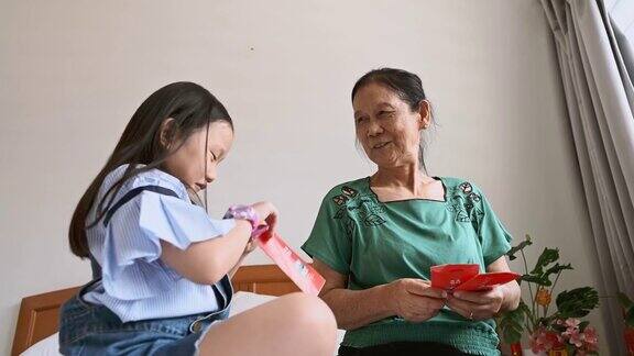 中国新年期间亚洲孙女在卧室问候和接受祖母的中国新年红包