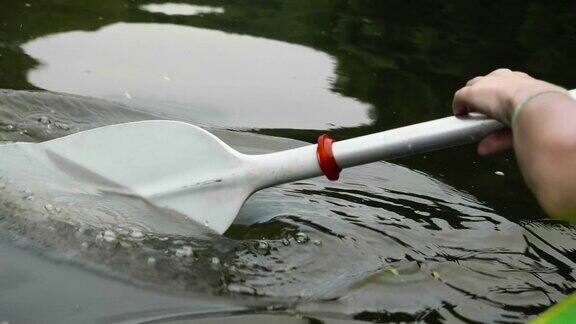 年轻的女孩在一个美丽的湖上划独木舟与近距离的桨
