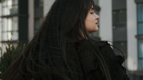 奇妙的发型可爱的年轻女子理想的发型模特在城市背景下摆姿势可爱的脸头发吹转身特写镜头