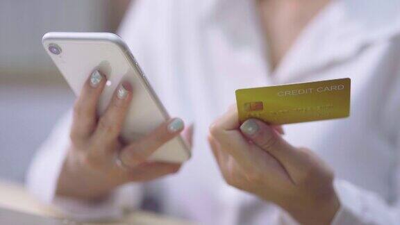 年轻女子在家使用手机和信用卡进行网上购物