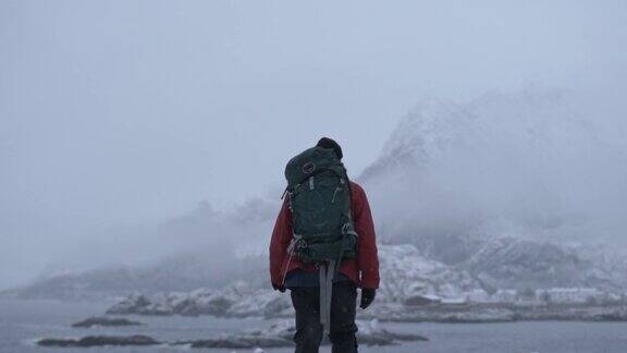 徒步旅行者穿过雪走向峡湾