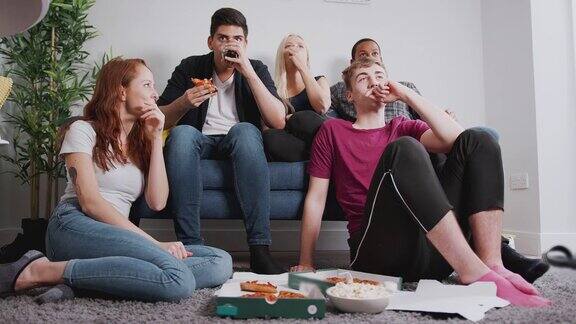 一群大学生朋友在一起看电视一起吃披萨-慢镜头