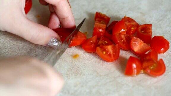 女性用手将樱桃番茄切成块